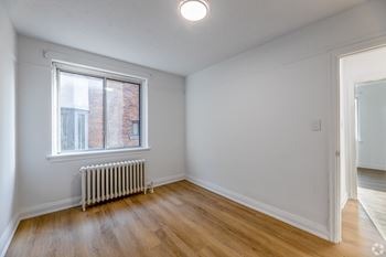 A room with a window and a radiator on the floor.